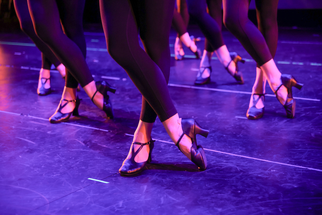 Close view of dancers' feet and character shoes in unison on the stage floor