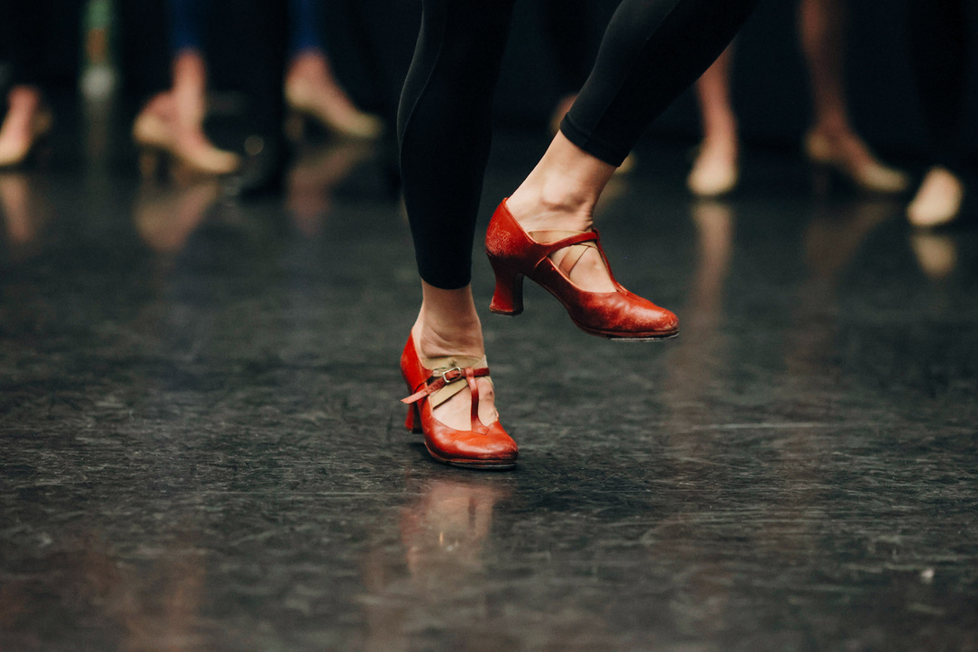 Close-up of red character heels mid-step on the studio floor